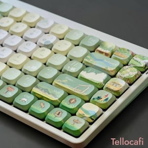 May include: A white and green keyboard with custom keycaps. The keycaps feature landscape designs with green, blue, and yellow hues. The keyboard has a gradient color scheme, transitioning from white to green. The brand name "Tellocafi" is visible.