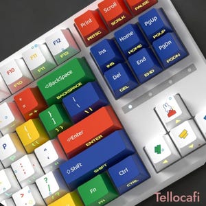 May include: A white mechanical keyboard featuring a multi-colored keycap set with red, blue, green, and yellow keys. The keys display white and yellow text, including standard function labels and a small graphic of a white rabbit on a red block.