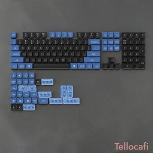 Peut inclure: Un ensemble de touches pour clavier mécanique composé de touches noires et bleues avec des lettres blanches. La disposition comprend un agencement QWERTY standard, un pavé numérique et des touches de remplacement bleues supplémentaires.