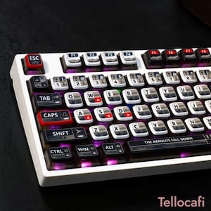 May include: A white mechanical keyboard with black and white keycaps. The keyboard has a red ESC key and a red CAPS key. The text "THE AEROLITE FALL DOWN" is printed on the bottom. The keyboard is lit with purple lights.