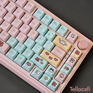May include: A pastel pink mechanical keyboard with light blue and pink keycaps. The keycaps feature various cute illustrations, including bears and hearts. The keyboard has a paw-shaped button and the text "Tellocafi".