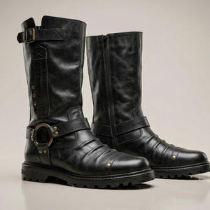 May include: A pair of black leather motorcycle boots. The boots have a tall shaft, buckles, and a zipper on one boot. The soles are thick and rugged. The boots are designed for durability and style.
