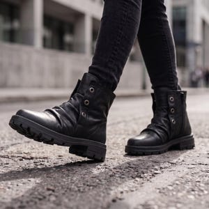 May include: A pair of black leather ankle boots featuring a ruched upper, a side zipper, and a vertical row of three silver-toned metal eyelets along the outer shaft. The boots have a thick, lugged rubber sole and are worn with dark denim jeans.