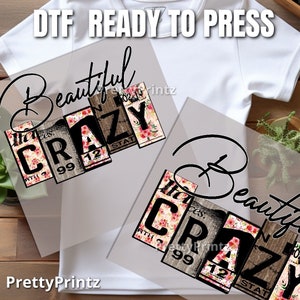 May include: A white t-shirt with a clear transfer sheet on top. The transfer sheet has a design that says "Beautiful Crazy" with a floral pattern. The design is made up of wooden blocks with black lettering.