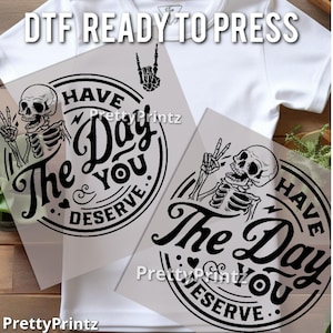 May include: Two black and white iron-on transfers featuring a skeleton with a peace sign and the text "Have the day you deserve."