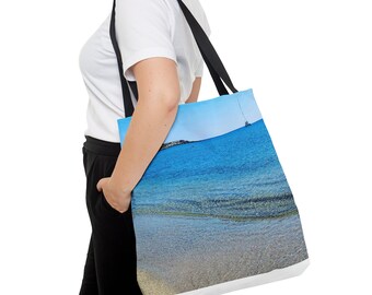 Puede incluir: Una bolsa de mano negra con fondo de lona blanca que presenta una fotografía de un océano azul con un velero en la distancia.