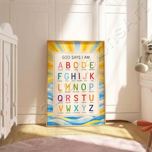 Könnte beinhalten: Ein gerahmter Druck mit dem Text "GOD SAYS I AM" und einem Alphabet mit positiven Affirmationen. Das Kunstwerk zeigt ein gelb-blaues Sonnenstrahlendesign mit hellem Hintergrund. Der Druck wird in einem Kinderzimmer ausgestellt.