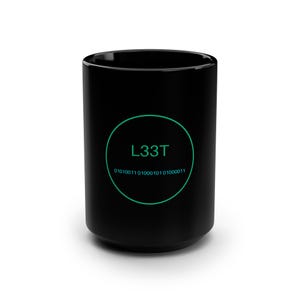 May include: A black ceramic mug featuring a green circular graphic on the front. Inside the circle, the text L33T is printed in green above a sequence of binary code in light blue, specifically 01010011 01000101 01000011.