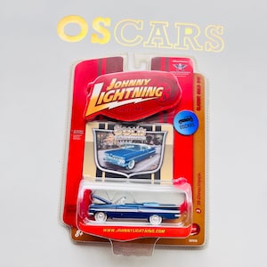 Peut inclure: Une voiture miniature bleue '59 Chevy Impala dans son emballage d'origine. L'emballage présente le logo Johnny Lightning et le texte "Classic Gold". La voiture miniature est un cabriolet avec des pneus à flancs blancs.