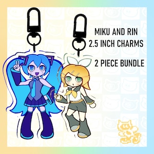 May include: Two 2.5 inch character charms featuring Miku and Rin from the Vocaloid series. The charms are attached to black keychains. The text "Miku and Rin 2.5 inch charms 2 piece bundle" is displayed on a white background.