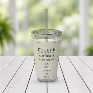 May include: A clear plastic tumbler with a lid and straw featuring a cream-coloured label printed with the text EUCHRE THE BOWERS, RIGHT BOWER, LEFT BOWER, ACE, KING, QUEEN, TEN, NINE in dark green and brown lettering on the front surface.