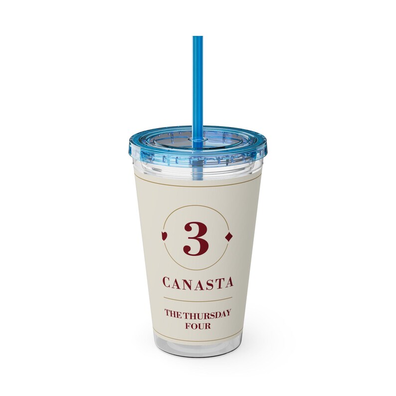 May include: A clear plastic tumbler with a blue lid and matching blue straw. The cup features a cream-colored insert printed with a large red number 3, the word CANASTA, and the text THE THURSDAY FOUR, framed by thin circular lines.