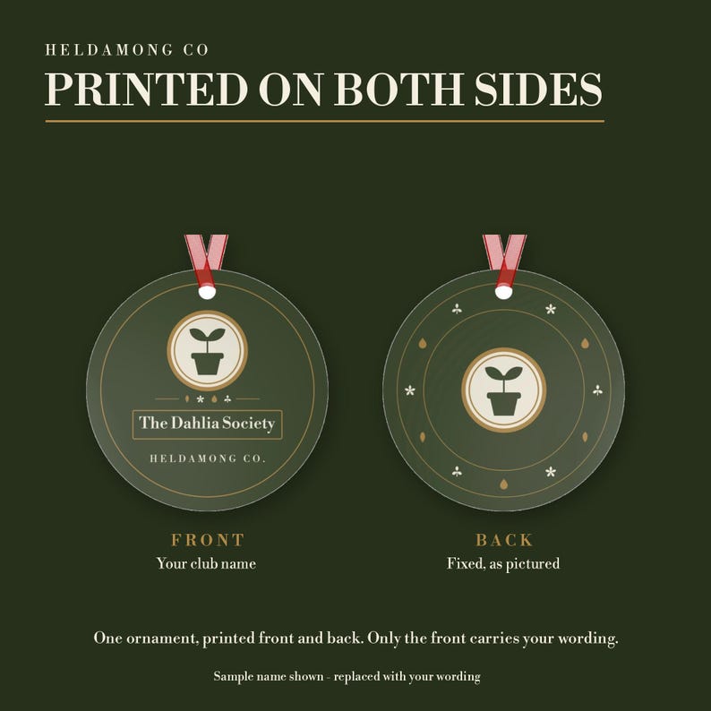 May include: Two round dark green ornaments with red ribbons. The front features a potted plant icon, the text 'The Dahlia Society' and 'HELDAMONG CO.' The back displays a potted plant icon surrounded by small symbols. Text reads 'PRINTED ON BOTH SIDES'.