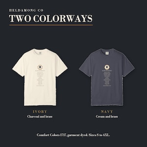 May include: Two short-sleeve t-shirts, one ivory and one navy, each featuring a central graphic with the text HELDAMONG CO, TWO COLORWAYS, and HAND RANKINGS. The ivory shirt has charcoal and brass text, while the navy shirt has cream and brass text.