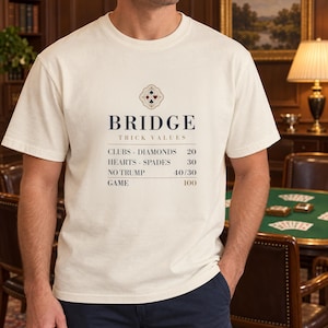 May include: An off-white short-sleeve t-shirt featuring a graphic print that reads BRIDGE TRICK VALUES with a list of card suits and their point values, including CLUBS, DIAMONDS, HEARTS, SPADES, NO TRUMP, and GAME, topped with a small card suit icon.