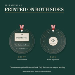 May include: A round dark green ornament with a red ribbon hanger. The front features the text HELDAMONG CO, PALMETTO MAHJONG CLUB, and The Palmetto Four. The back displays a circular logo with a four-petal symbol and the text HELDAMONG CO.