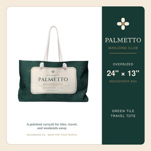 May include: An oversized dark green weekender bag featuring a repeating mahjong tile pattern and white rope handles. A central cream-colored rectangular label displays the text Palmetto Mahjong Club, Hilton Head Island, Est 2024, 24 inches by 13 inches.