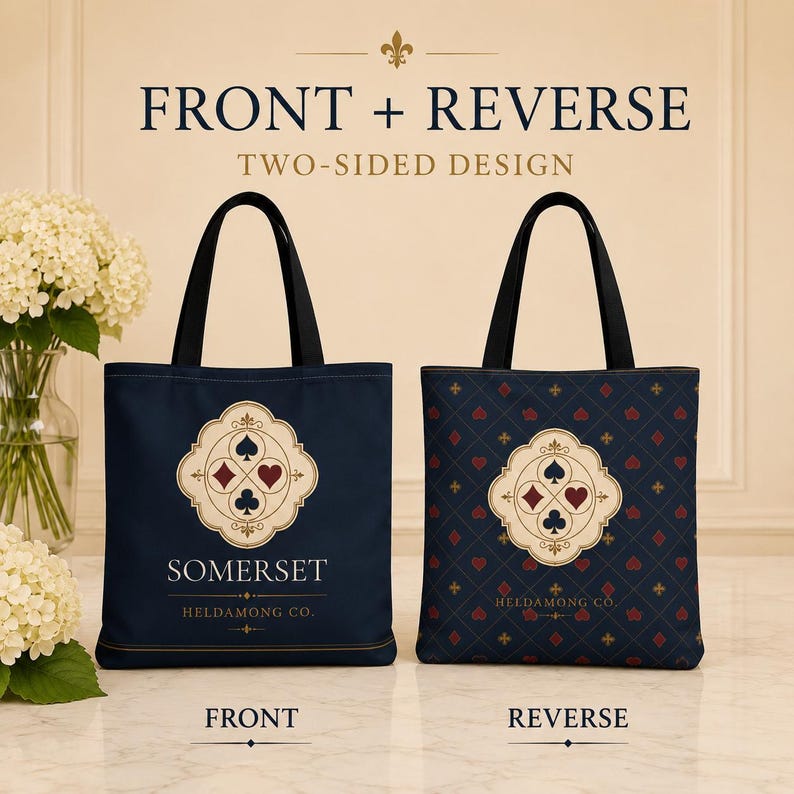 May include: Two tote bags with black handles. The left bag is navy blue with a central cream emblem featuring four card suits and the text SOMERSET HELDAMONG CO. The right bag has a navy blue diamond pattern with red hearts and gold symbols.