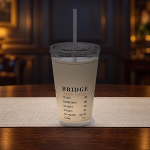 以下が含まれることがあります： 蓋とストローが付いた透明なプラスチック製タンブラー。ベージュのラベルにはブリッジのトリック値が印刷されています。カップには、Clubs 20、Diamonds 20、Hearts 30、Spades 30、No Trump 40/30、Game 100というテキストが黒いセリフ体で記載されています。