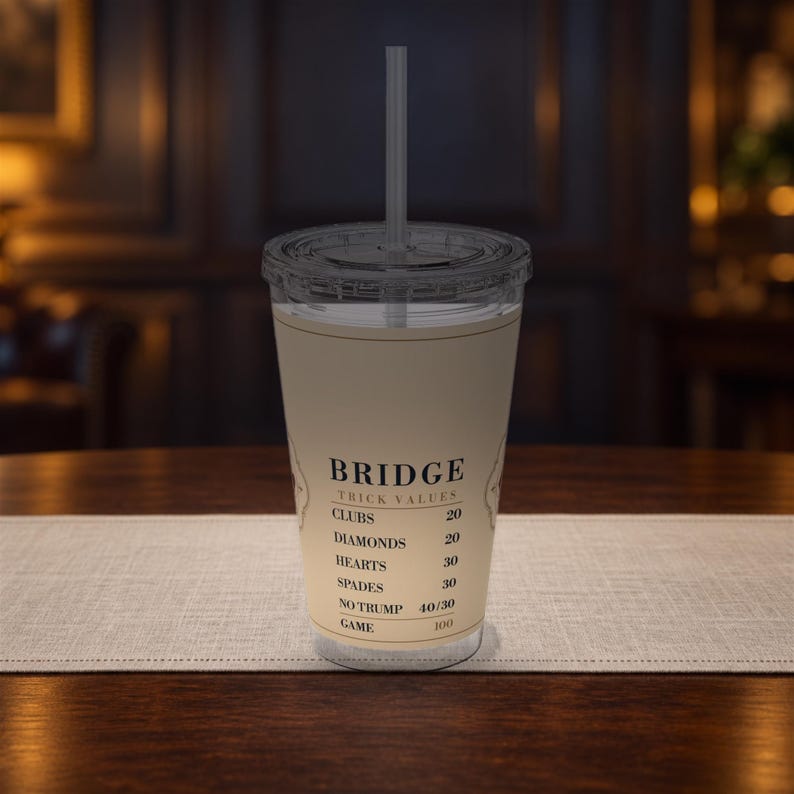 以下が含まれることがあります： 蓋とストローが付いた透明なプラスチック製タンブラー。ベージュのラベルにはブリッジのトリック値が印刷されています。カップには、Clubs 20、Diamonds 20、Hearts 30、Spades 30、No Trump 40/30、Game 100というテキストが黒いセリフ体で記載されています。