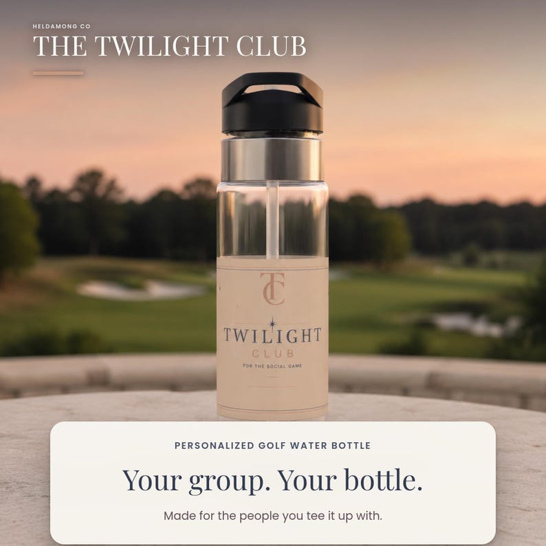 May include: A clear water bottle with a black lid and a straw, featuring a beige label with the text THE TWILIGHT CLUB, a TC logo, and the phrase FOR THE SOCIAL GAME. The bottle is positioned against a blurred outdoor golf course background.