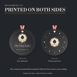May include: Two round ornaments with red ribbons, featuring a black background and a beige poker chip graphic with a spade. The front displays the text "The Friday Game" and "HELDAMONG CO." while the back shows a pattern of card suit symbols.
