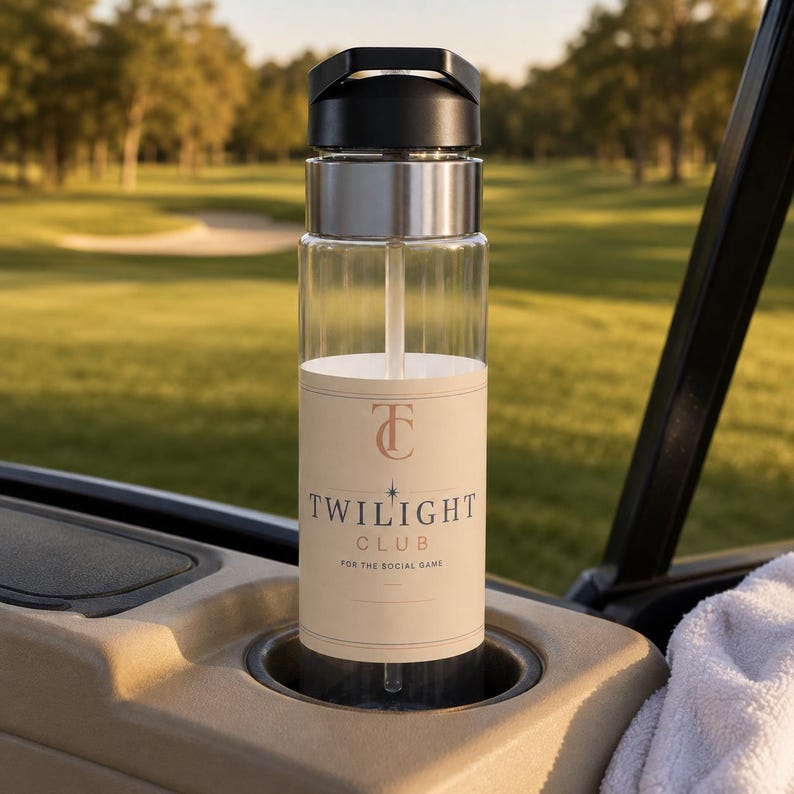 May include: A clear water bottle with a black lid and a straw, featuring a beige label with the text "TC TWILIGHT CLUB FOR THE SOCIAL GAME" in dark lettering. The bottle is cylindrical with a metallic silver band below the black cap.