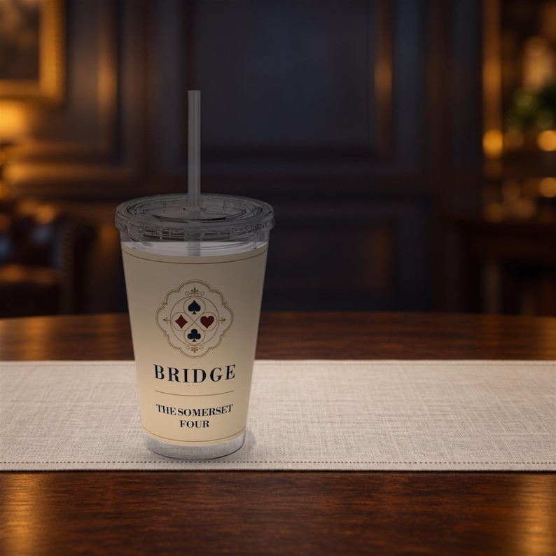 May include: A clear plastic tumbler with a lid and straw, featuring a cream-colored label with a decorative border containing four card suit symbols. The text reads BRIDGE and THE SOMERSET FOUR in black, centered on the front of the cup.