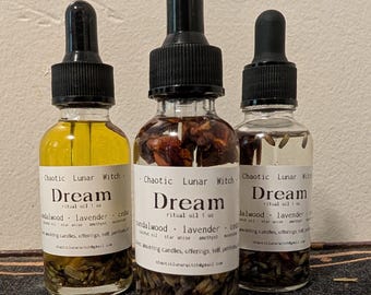 Puede incluir: Tres frascos cuentagotas de vidrio transparente con la etiqueta Dream ritual oil 1 oz de Chaotic Lunar Witch. Los frascos contienen líquido con inclusiones botánicas visibles como lavanda y trozos de madera, con tapas negras.