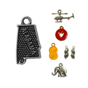 May include: A set of silver charm pendants featuring an outline of the state of Alabama, a peanut, a heart, an elephant, and a helicopter.