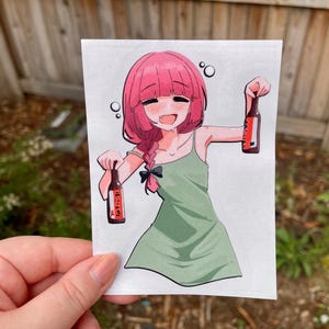 Puede incluir: Adhesivo de estilo anime que muestra a una chica con pelo rosa sosteniendo dos botellas de cerveza. Lleva un vestido verde y un lazo negro en el pelo. Las botellas tienen texto japonés.