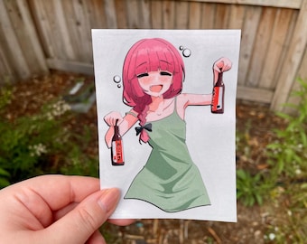 Op de afbeelding: Anime-stijl sticker met een lachend meisje met roze haar dat twee flessen bier vasthoudt. Ze draagt een groene jurk en heeft een zwarte strik in haar haar. De flessen hebben Japanse tekst.