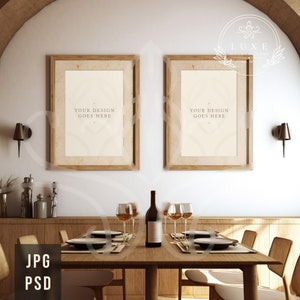 May include: Two wooden framed pictures with the text "Your design goes here" hanging on a white wall above a wooden dining table set with wine glasses, a bottle of wine, and plates.