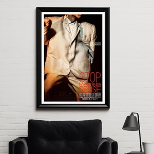 May include: A black and white movie poster for the film "Stop Making Sense" featuring a man in a white suit and the film title in red text.