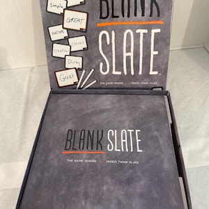Puede incluir: Caja de juego de mesa abierta, gris, con el t&iacute;tulo "BLANK SLATE" en letras blancas. El juego incluye tarjetas con palabras como "Simple", "Awesome" y "Creative". El juego est&aacute; dise&ntilde;ado para 3-8 jugadores.