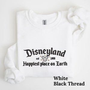 May include: White sweatshirt with black text that reads "Disneyland est. 1955 Happiest place on Earth" with a black and white Mickey Mouse head graphic. The text "White Black Thread" is printed in black at the bottom of the image.