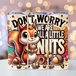 May include: A set of three stainless steel insulated tumblers with a cartoon squirrel design. The squirrel is holding an acorn, and the text reads "Don't Worry We Are All A Little Nuts". The tumblers have a clear lid.