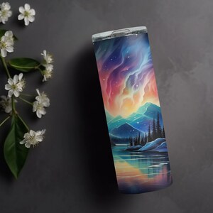Puede incluir: Un vaso de acero inoxidable con una escena de monta&ntilde;a colorida y un reflejo del cielo en el agua. La escena presenta una cordillera con un lago en primer plano y un cielo colorido con estrellas y nubes.