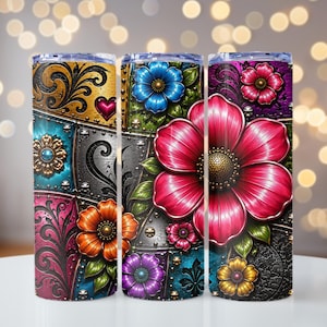May include: Three stainless steel insulated tumblers with floral designs. Each tumbler features a patchwork design with vibrant colors, including gold, pink, blue, orange, and purple. The floral elements include large and small flowers with intricate details.