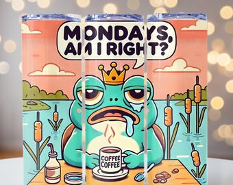 May include: A set of three stainless steel insulated tumblers with a cartoon frog design. The frog wears a crown and holds a coffee cup, with the text "MONDAYS, AM I RIGHT?" in a speech bubble. The background features a lake scene.