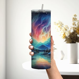 Puede incluir: Un vaso de acero inoxidable con una escena colorida de monta&ntilde;a y lago. El dise&ntilde;o presenta un cielo vibrante similar a una aurora boreal con un reflejo en el agua.