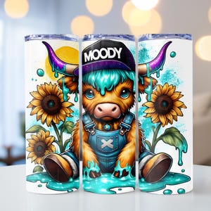 Könnte beinhalten: Ein weißer Becher mit einer bunten Illustration einer Comic-Kuh, die einen blauen Hut mit dem Wort "MOODY" trägt. Die Kuh sitzt in einer Pfütze blauer Farbe mit Sonnenblumen im Hintergrund.