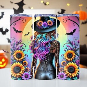 May include: A stainless steel tumbler with a colourful design featuring a witch with rainbow hair, sunflowers, and bats. The background is a sunset with a full moon.