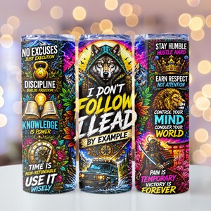 May include: Three cylindrical tumblers featuring vibrant, multi-colored graphic designs. The tumblers display motivational text including 'No Excuses', 'I Don't Follow I Lead By Example', and 'Stay Humble', alongside illustrations of a wolf, lion, and samurai.