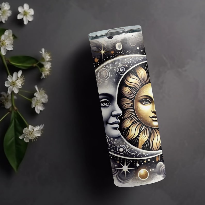 Puede incluir: Un vaso de acero inoxidable con un dise&ntilde;o negro, blanco y dorado de una luna creciente y el sol sobre un fondo estrellado.