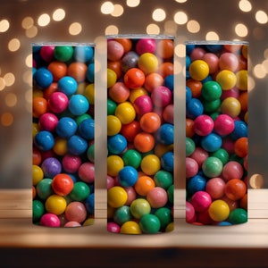 Pode incluir: Três copos de aço inoxidável com um design de gomas de mascar coloridas. Os copos estão cheios de uma variedade de cores, incluindo vermelho, laranja, amarelo, verde, azul e roxo.