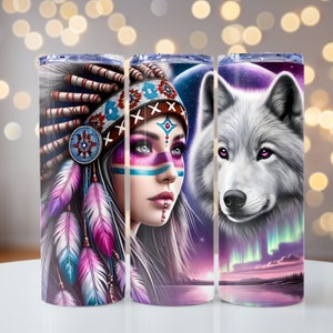 May include: Three stainless steel tumblers with different designs. The first tumbler features a woman with a colourful headdress and face paint. The second tumbler features a woman with a colourful headdress and face paint, and a wolf. The third tumbler features a wolf with a colourful aurora borealis in the background.