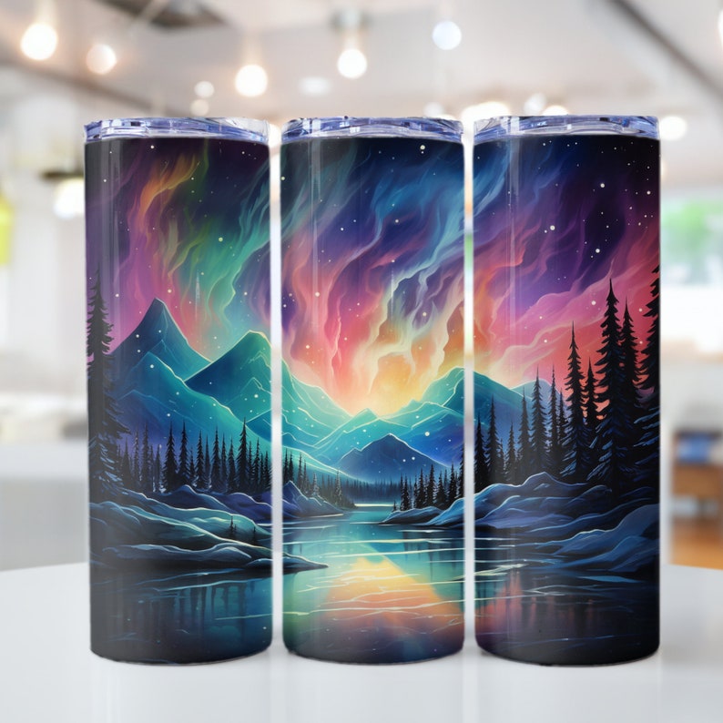 Puede incluir: Tres vasos de acero inoxidable con un dise&ntilde;o de aurora boreal colorido. El dise&ntilde;o presenta una cordillera, un lago y un bosque silueteados contra la aurora.