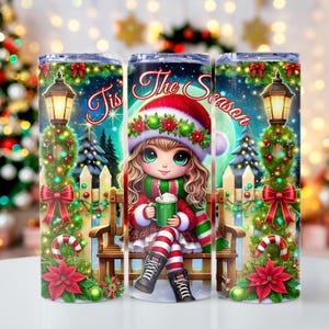 May include: A set of three stainless steel tumblers with a Christmas theme. The tumblers feature a cartoon girl in a red and white Santa hat, sitting on a bench with a cup of hot chocolate. The text "Tis the Season" is written on the tumblers.
