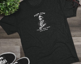 May include: A dark grey t-shirt with a white graphic of a man playing a guitar. The text on the shirt reads "Mama tried but I think I'll just stay here and drink."